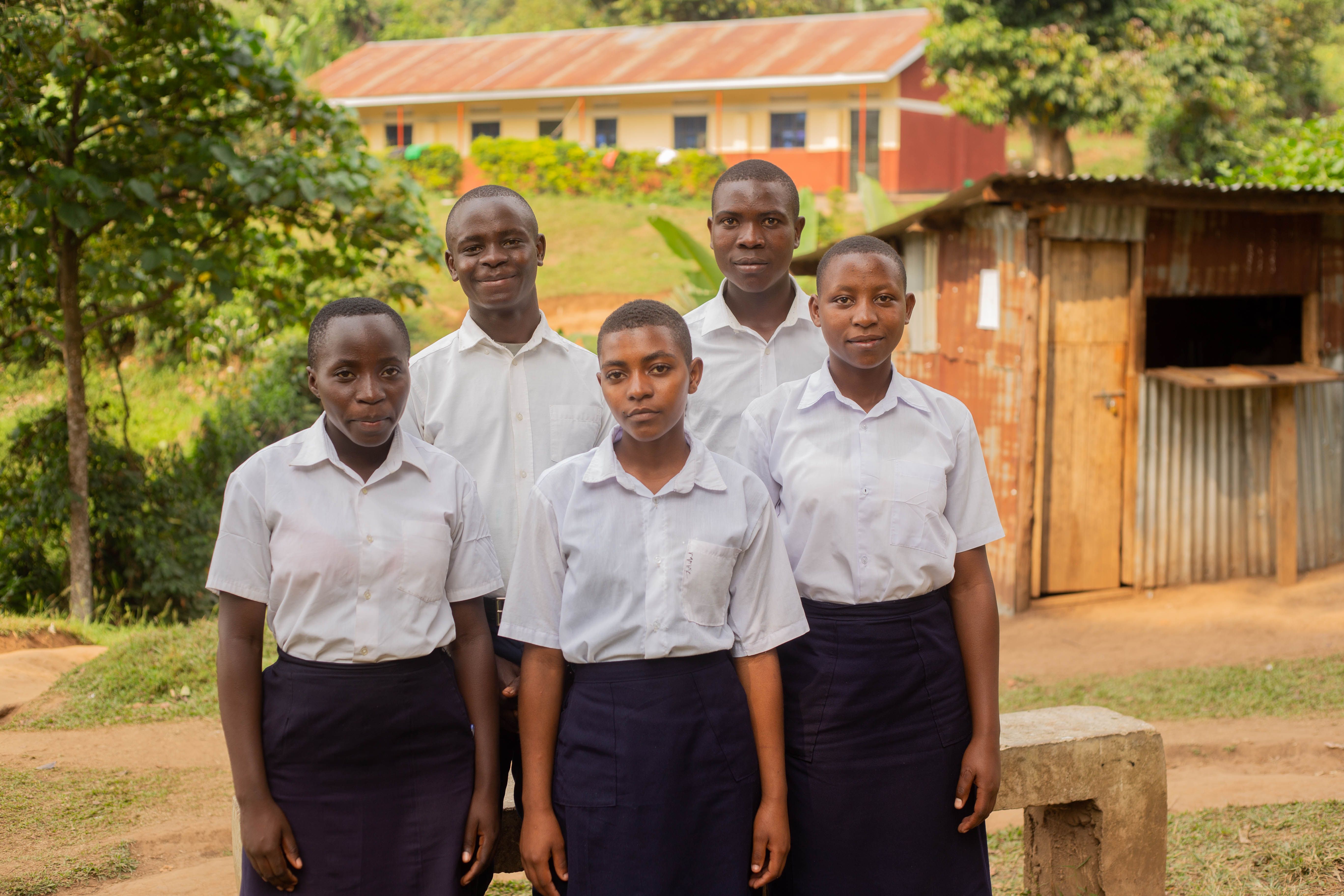 A group of secondary school students in uniform standing outside their school