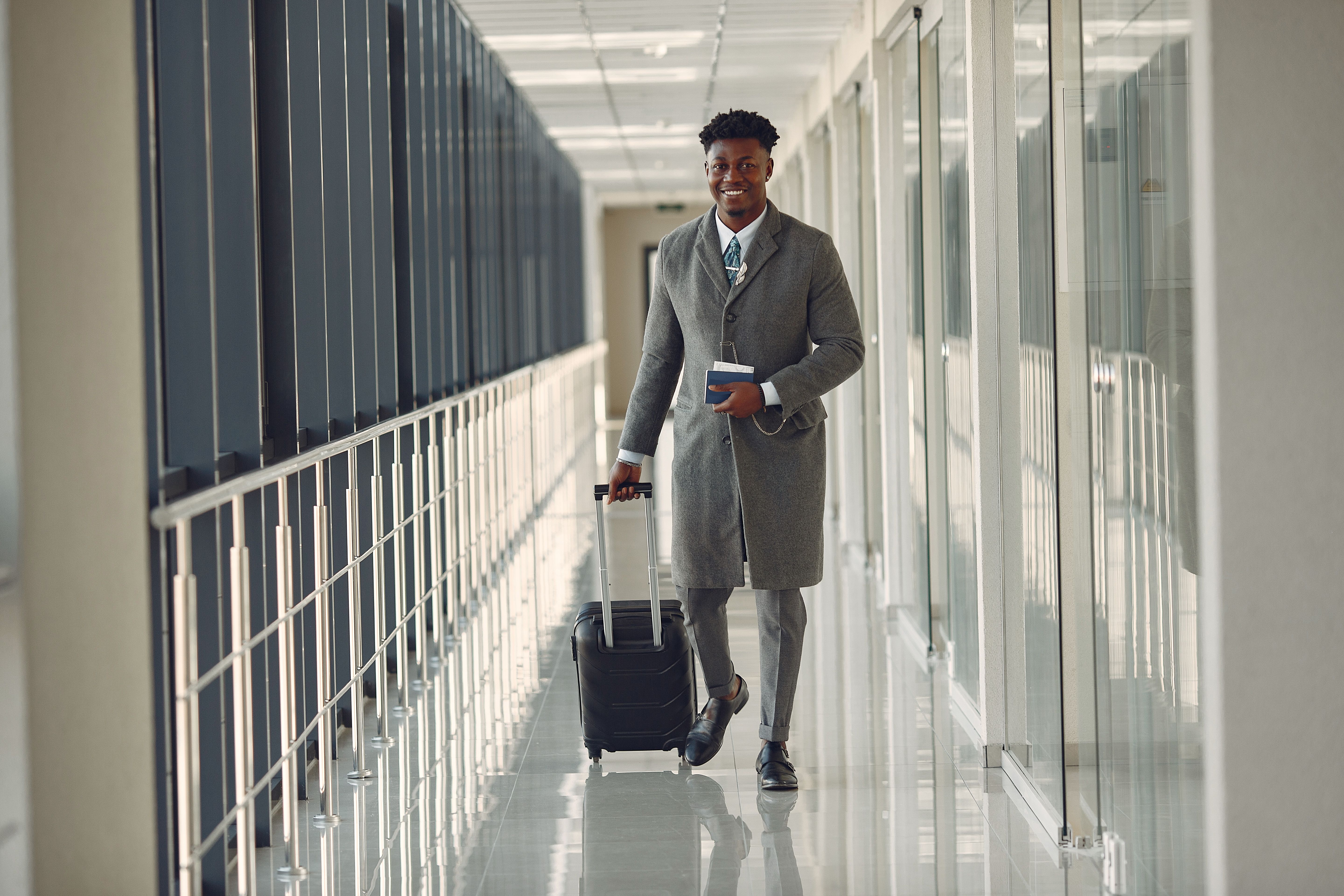 A traveler walking through an airport with a suitcase and passport